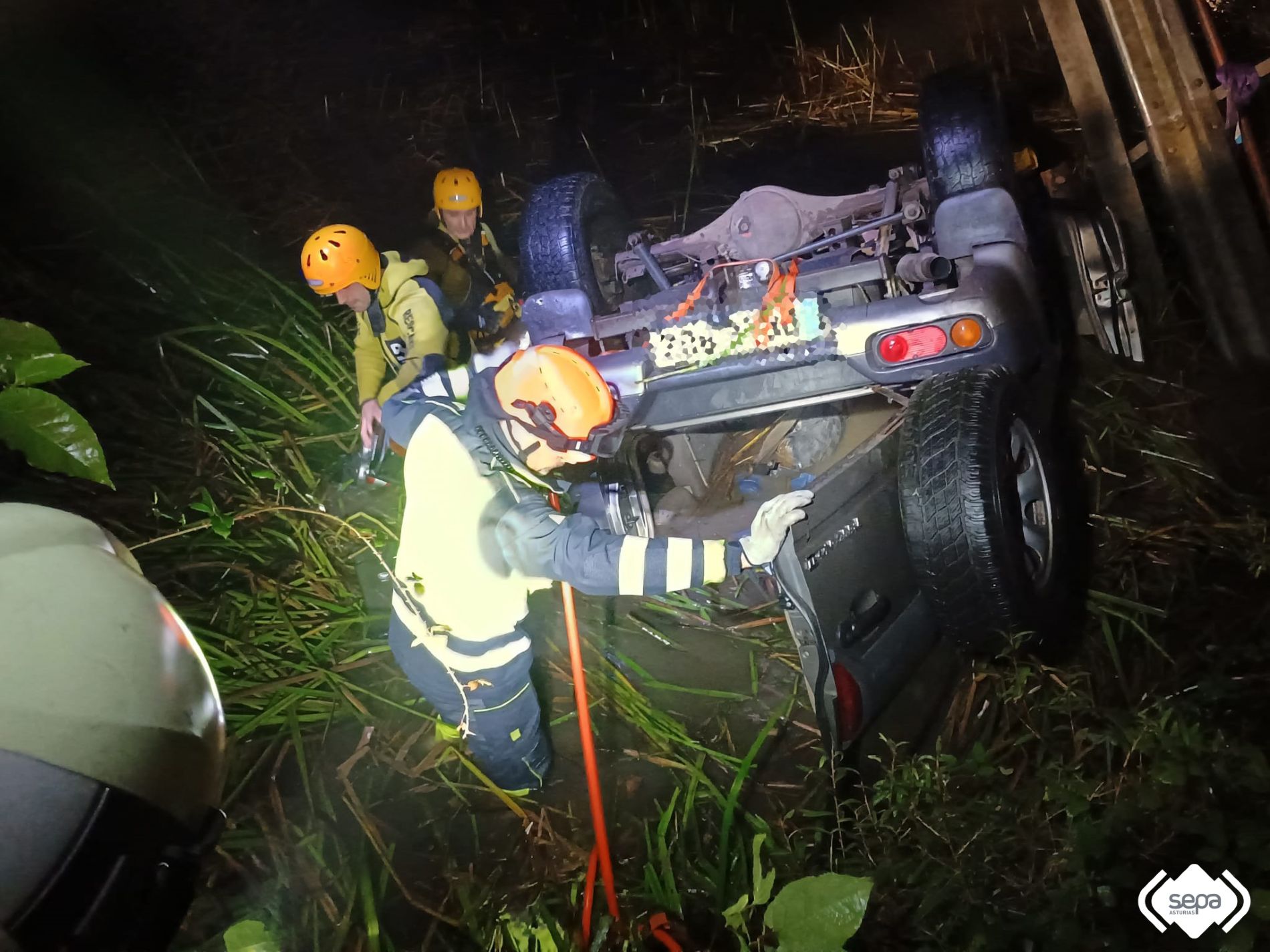 Bomberos con el vehculo accidentado en Ozanes, Parres.